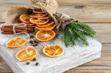 Noel kompozisyonu ladin ağacı dalları, tarçın çubukları ve ahşap zemin üzerinde kurumuş portakal dilimlerinden yapılmış çelenkler. Kırsal biçim