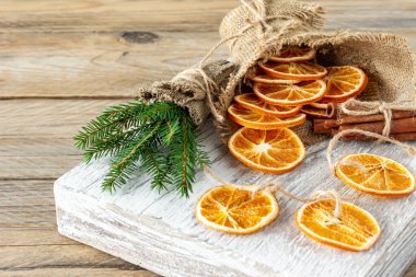 Noel kompozisyonu ladin ağacı dalları, tarçın çubukları ve ahşap zemin üzerinde kurumuş portakal dilimlerinden yapılmış çelenkler. Kırsal biçim