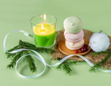 Ev yapımı pastel, yuvarlak renkli zephyr, yeşil mum ve köknar dallarıyla noel kompozisyonu.