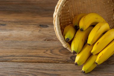 Tahta arka planda hasır sepette muz parçaları. Sağlıklı yeme kavramı.