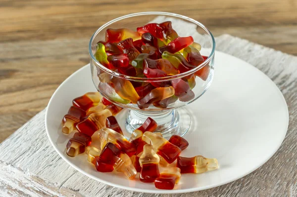 Kauwende Marmelade Flessen Cola Beren Witte Plaat Houten Ondergrond — Stockfoto