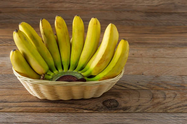木製の背景にウィカーバスケットにバナナのリップ束 健康的な食事のコンセプト — ストック写真
