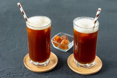 Gri arka planda buzlu kahveli iki uzun bardak, yaz içeceği.