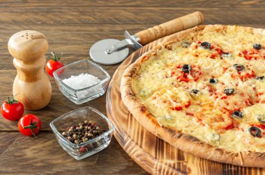 Acı biberli, domatesli, siyah zeytinli ve ahşap tahtada mozzarella soslu sıcak pizza.
