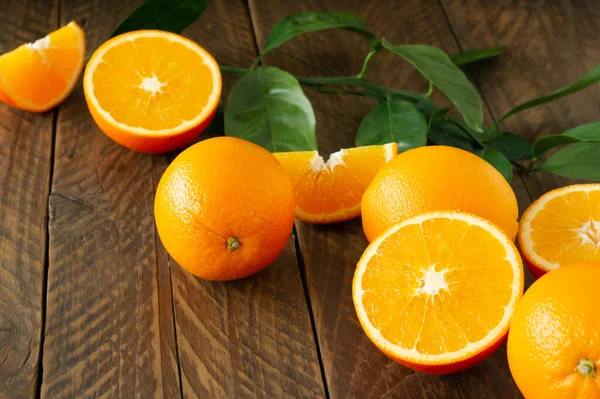 Kırsal ahşap arka planda yeşil saçaklı taze portakallar.