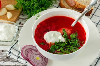 Geleneksel Ukrayna Rus pancar çorbası, sarımsak ve ekmek. Beyaz ahşap bir masada bir kase kırmızı pancar çorbası. Pancar çorbası. Geleneksel Slav mutfağı