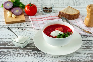 Geleneksel Ukrayna Rus pancar çorbası, sarımsak ve ekmek. Beyaz ahşap bir masada bir kase kırmızı pancar çorbası. Pancar çorbası. Geleneksel Slav mutfağı