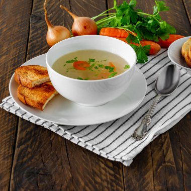 Kırsal ahşap arka planda beyaz kasede kızarmış tavuk bulyonu.