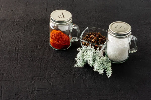 pepper and salt glass shakers on a black concrete backgroun with copy space.