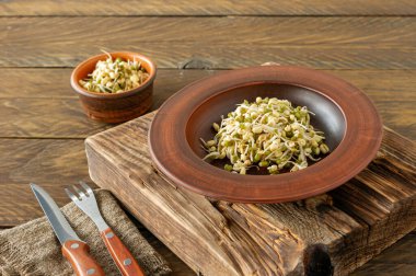 Yetiştirilmiş gıda. Kırsal ahşap arka planda bir tabakta filizlenmiş fasulye. Makrobiyotikler.