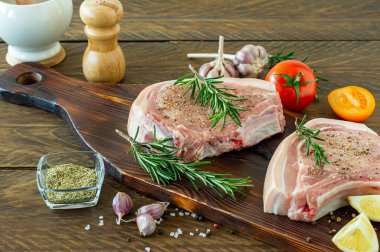 Baharatlı, baharatlı, biberiyeli, ahşap arka planda tuz ve biberli çiğ domuz eti parçaları. .