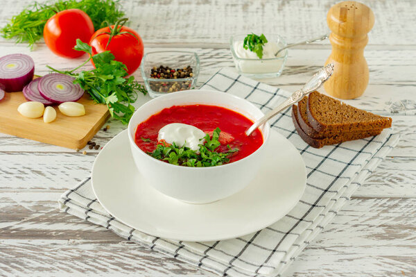 Traditional Ukrainian Russian borscht with garlic and bread. A bowl of red beetroot borscht on a white wooden table. Beetroot soup. traditional slavic cuisine