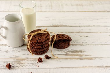 Chocolate cookies for breakfast with a glass of milk on a white wooden table