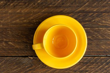 Boş sarı fincanın ve ahşap sahanlıkta uçan dairenin en üst görüntüsü. Mutfak çanağı..