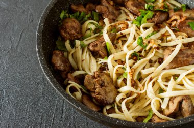 Maydanozlu pişirme kaleminde soğanlı tavuk ciğeri ve spagetti. Lezzetli bir aile yemeği..