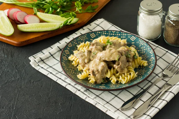 Italian whole grain pasta with roasted chicken liver and onions served on a plate on marble background.