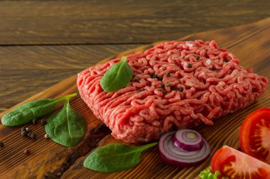 Tahta kesme tahtasında sebze ve baharatla doğranmış çiğ et. Yemek pişirme ve sağlıklı yeme konsepti