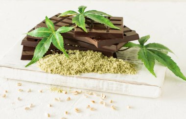 Beyaz arka planda marihuana yaprakları ve koyu çikolata.