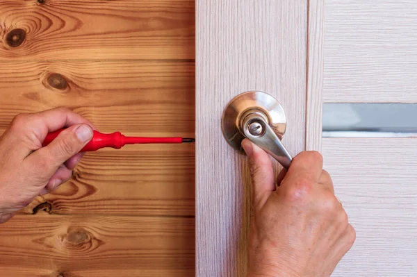 Close-up Of Man\'s Hand Installing Door Lock At Home.