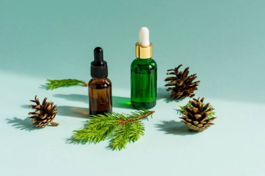 Mavi arka planda küçük cam damlacıklar içinde çam ve ladin yağı.