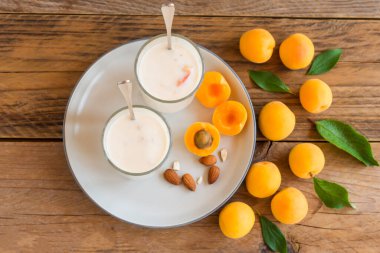 Şeftali tatlısı porsiyon bardakta, şeftali dilimleri ahşap masada, kapat..