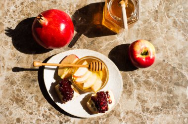 Rosh Hashanah kartpostalında mermer arka planda elma, nar ve bal olsun..