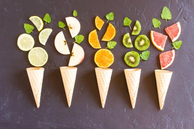 Siyah arka planda meyveli waffle konileri. Yaratıcı gıda konsepti. en üstteki görünüm.