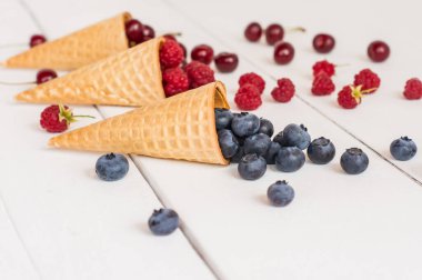 Beyaz ahşap bir masada yaz meyveleri ile nefis waffle külahları. yan görünüm