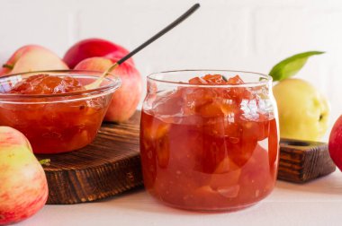 şeffaf elma reçeli cam bir kavanozda beyaz tuğla bir duvara yakın planda lezzetli ve güzeldir.