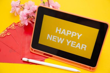 Sarı arkaplanda kablosuz klavye izole edilmiş dijital tablet ekranda Mutlu Yıllar metni