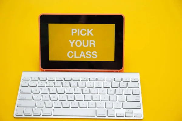 Sarı arkaplanda kablosuz klavye izole edilmiş dijital tablet ekranında sınıfınızın metnini seçin
