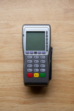 Tahta bir masanın üzerindeki kart ve çek terminalinin dikey görüntüsü