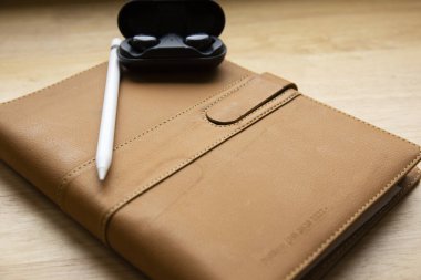 Tablette kablosuz kulaklık ve tahta arka planda kalem.