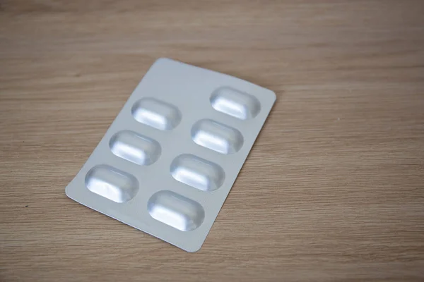 Ahşap yüzeydeki gri ve pembe ilaç listelerinin genel görüntüsü.