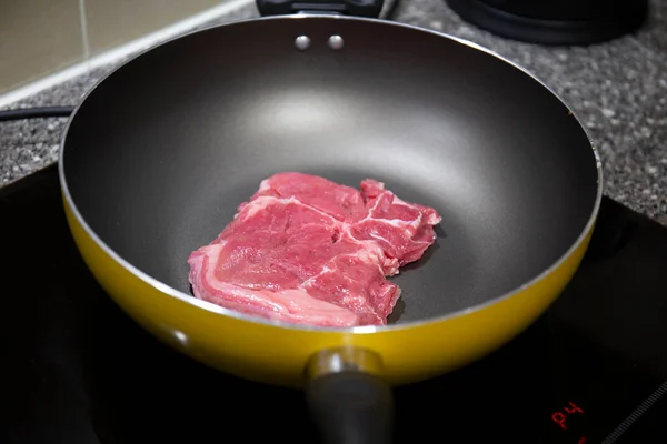 Mutfaktaki fırının tepsisindeki çiğ et parçasının yakın çekimi.