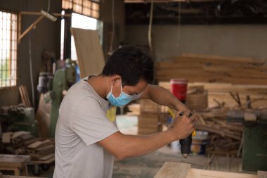 Marangozun atölyedeki elektrikli matkabı kullanarak ve dolap yapımcısının masaya odun deldiği delikleri açarak yakın plan görüntüsü. Ahşap mobilyaların yapımı ve yenilenmesi üzerine doğrama işleri. Küçük İş