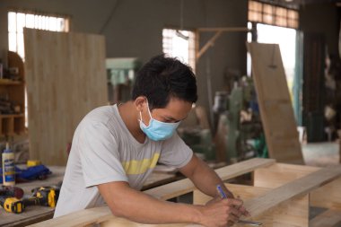 Marangoz atölyede cetvelle ahşap tahtayı ölçüyor. Ahşap mobilya üretiminde doğrama işi. Küçük İş Konsepti