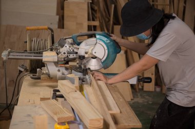 Marangoz atölyede elektrikli testere ile ahşap üzerinde çalışıyor. Ahşap mobilya üretiminde doğrama işi. Küçük İş Konsepti