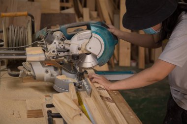 Marangoz atölyede elektrikli testere ile ahşap üzerinde çalışıyor. Ahşap mobilya üretiminde doğrama işi. Küçük İş Konsepti