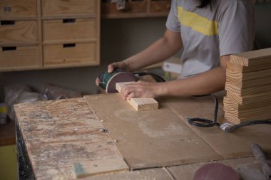 atölyedeki elektrikli zımpara makinesini kullanarak ahşap ile çalışan bir arpenter. Ahşap mobilyaların yapımı ve yenilenmesi üzerine doğrama işleri. Küçük işletme konsepti. Kapat.