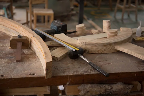 Marangoz aleti ve ürünü atölyedeki bir masanın üzerinde. Çekiç, cetvel, matkap