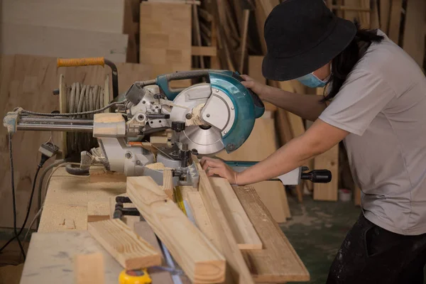 Marangoz atölyede elektrikli testere ile ahşap üzerinde çalışıyor. Ahşap mobilya üretiminde doğrama işi. Küçük İş Konsepti