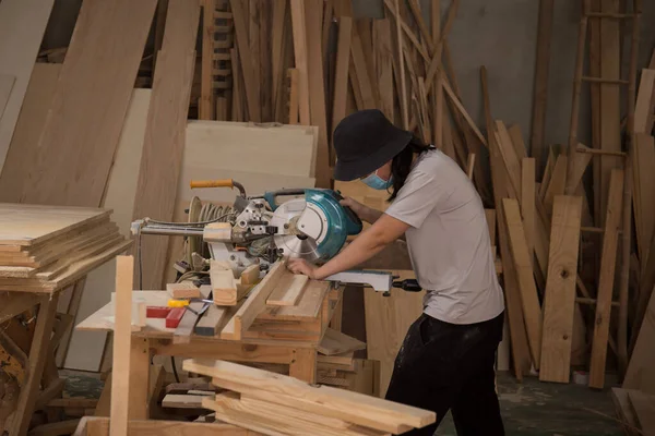 Marangoz atölyede elektrikli testere ile ahşap üzerinde çalışıyor. Ahşap mobilya üretiminde doğrama işi. Küçük İş Konsepti