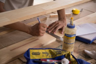 Marangoz atölyede cetvelle ahşap tahtayı ölçüyor. Ahşap mobilya üretiminde doğrama işi. Küçük İş Konsepti