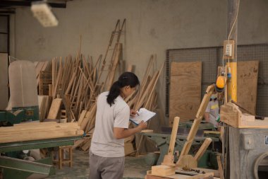 Genç erkek marangoz arkada çalışırken müşteri yağını kontrol ediyor. 