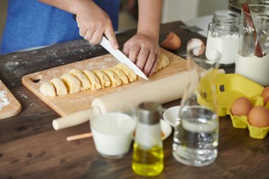 Ev yapımı makarna için hamuru kes. Kadın hamuru bıçakla kesiyor. Makarna için, ahşap masada..