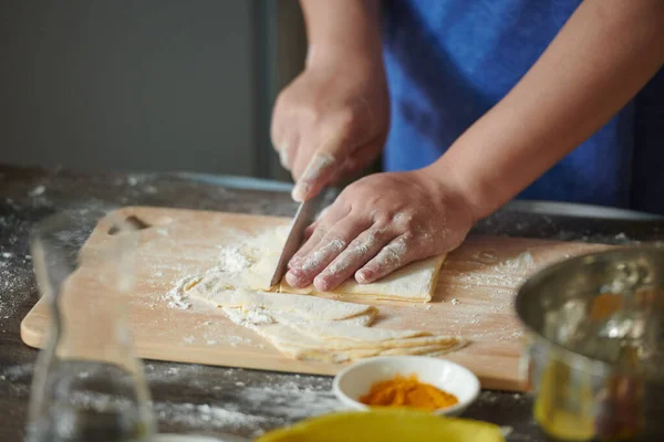 Kadın eli masanın üzerinde Wonton yaprağını kesiyor. 