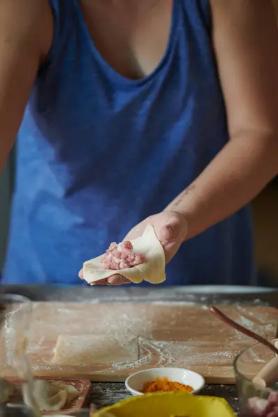 Kadının ellerinin ahşap raptiyeyle etli hamur tatlısı yaptığı ön manzara. Ev yapımı hamur tatlısı yapma süreci. Hamurda kıyma, İtalyan mantısı pişirme süreci. Rus yemeği.