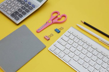 Okul tedarikçilerinin üst görünümü, hesap makinesi, kablosuz klavye sarı üzerinde izole 