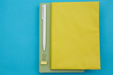 Yeşil ve sarı kitabın üst görüntüsü ve mavi arkaplanda izole edilmiş beyaz kalem 